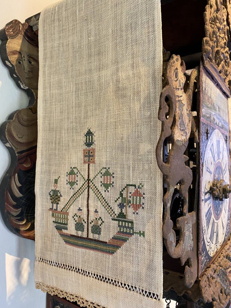 Traditioneel met de hand geborduurd klokkenkleedje op de kap van een antieke Friese staartklok